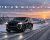 O'Hare winter travel from Wisconsin, with a black Cadillac Escalade driving on a snowy interstate highway at dawn with plowed lanes and falling snow